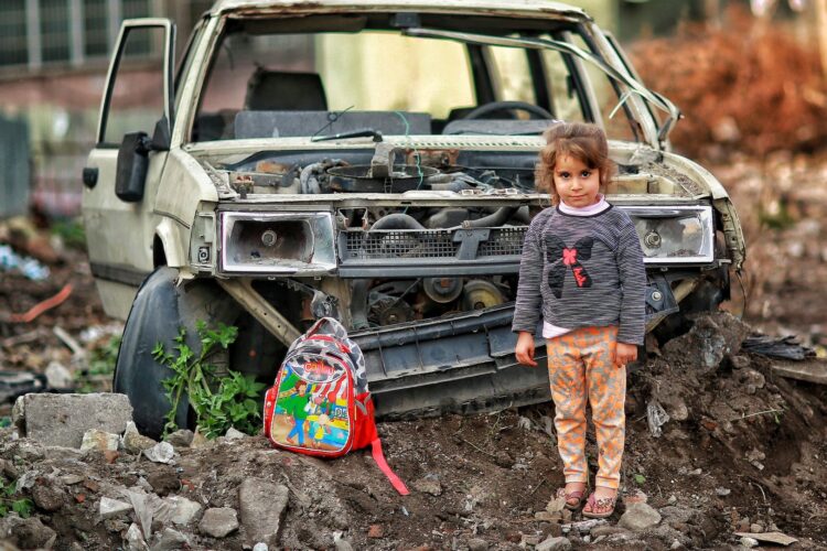 girl with backpack near broken car ruins