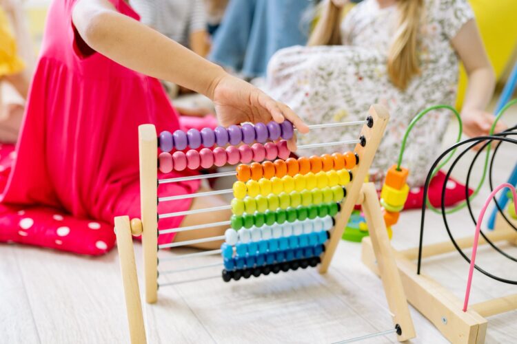 girl holding multi colored wooden abacus